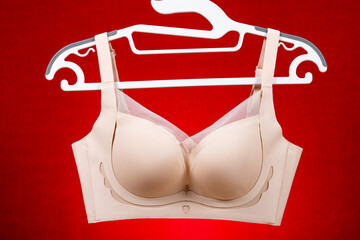 beige bra hanging on red background