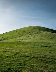 Serene green hill under a vast blue sky.