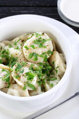 Dumplings with sour cream on a black wooden background