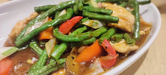 Colorful vegetables, chicken, and green beans stir-fried in a soy-based savory and rich sauce, captured in a close-up showcasing culinary detail.