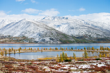 Russia. Magadan Region. Beautiful Lake Momontay against the backdrop of a snowy mountain range. Late autumn in the vicinity of Lake Momontay.