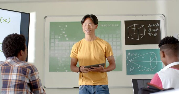 In high school, asian male student holding tablet and presenting students in classroom