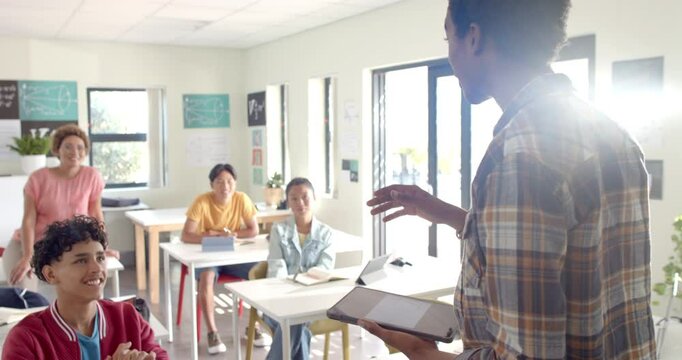 In high school, teenager presenting to classmates while holding book in classroom