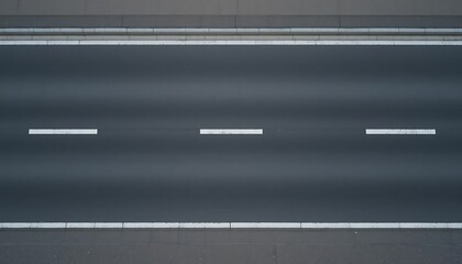 High-angle view of a dark gray asphalt road with white lane markings and curbs, ideal for backgrounds and textures.