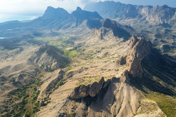 Aerial view of rugged mountains, coastal valley, ocean background, travel brochure