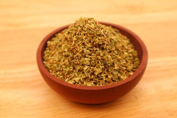 Dried oregano leaves or Origanum vulgare L. In a wooden bowl, close up view.