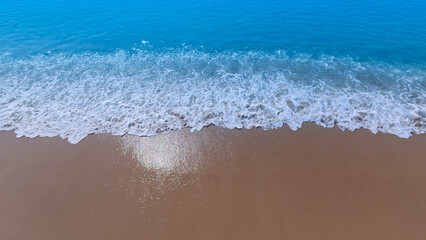 Tropical Beach with the soft wave water of the sea on the sandy beach background as texture with splashes and bubbles
