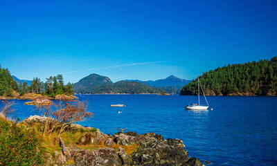 Vancouver Canada, Bowen Island. Boat and yacht in the bay of  northern sea against the background of mountain range, blue sky and wooded islands  
