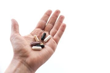 Closeup of a caucasian open hand holding daily supplement pills with off-white background and text...
