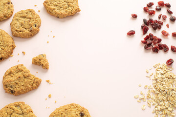 top angle view of oatmeal cranberry cookis and oats and dried cranberrries as ingredients with copy space