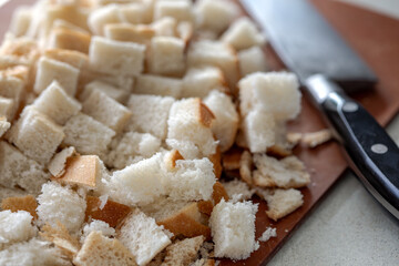 Closeup view of cubed white sourdough bread and kitchen knife on the cutting board