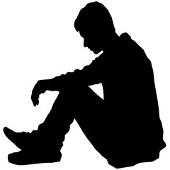 A man is sitting on the ground. He is wearing a black shirt and black pants. He is looking down
