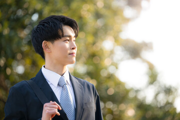 屋外でスーツを着た目標や未来を見つめる若い新卒のような男性　秋冬