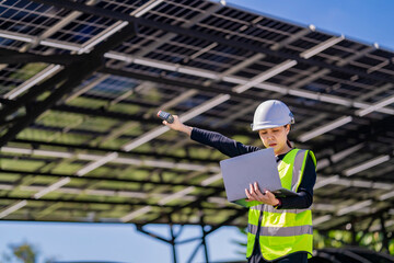 Engineer in safety vest and helmet pointing towards a solar powered carport, illustrating...