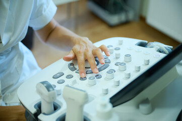 Crop view of a doctor at the ultrasound scanner. Radiology concept. Non invasive examination....