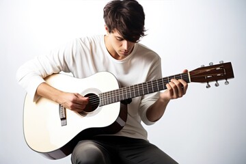 Obraz premium Young male musician showcases his passion and skill. A guitarist guy is playing an acoustic guitar in a recording studio with a white background