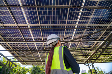 Engineer inspecting solar panels under a solar-powered carport on a sunny day, ensuring optimal...