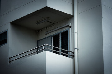 A balcony with a railing and a window. The railing is silver and the window is white. The balcony...