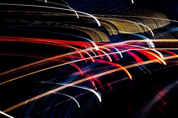 A series of bright lights are streaking across the sky. The lights are red, yellow, and blue....