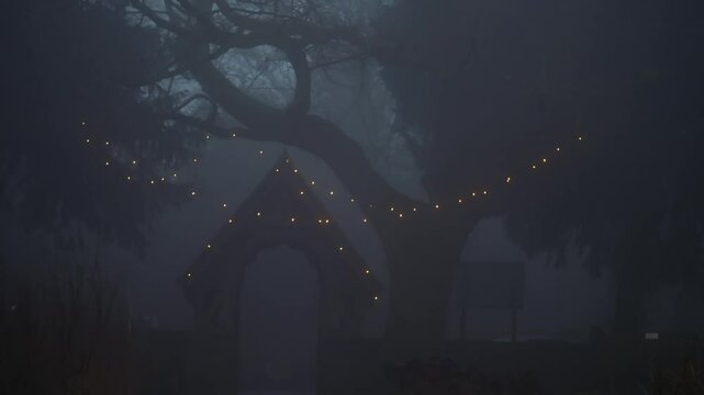 Lych gate at Church Entrance on winter foggy misty day covered in lights 