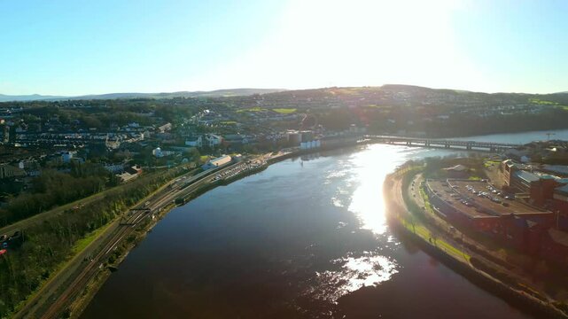 Aerial shot of the Derry City in Derry-Londonderry, NI on a sunny day. Showing the River Foyle and the Bogside and Waterside areas of the city. Filmed in 4K at 60fps and in Rec709 color space.