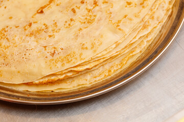 A stack of golden pancakes on a silver plate
