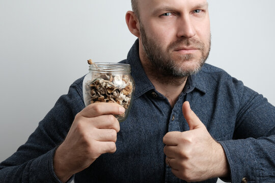 Dried Psilocybin mushrooms Psilocybe cubensis "Golden Teacher" in the hand of a middle-aged man. Concept of microdosing using natural psychedelics