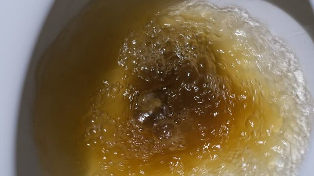 Flushing dirty poop toilet with foam-covered water surface, showcasing modern bathroom hygiene, sanitation concept, and water splash detail in domestic or commercial restroom interior.