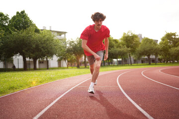 Man running along an outdoor running track during sunset