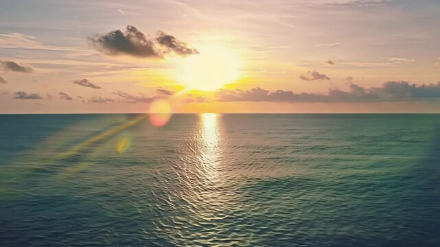 A peaceful ocean sunrise with warm golden light reflecting on the calm water, creating a tranquil and breathtaking seascape with scattered clouds.  View from above 4k video footage.

