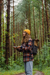 Young female hiker with backpack and yellow beanie using smartphone gps app for navigation on...