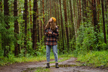 Young female hiker with backpack is using smartphone gps app enjoying hiking trail in the forest...
