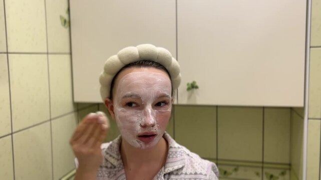 young teeneger girl making white facial mask in her own green bathroom. skincare, face cream morning evening rotine