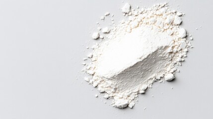 White powdery substance is spread out on a white surface. The powder is white and he is flour