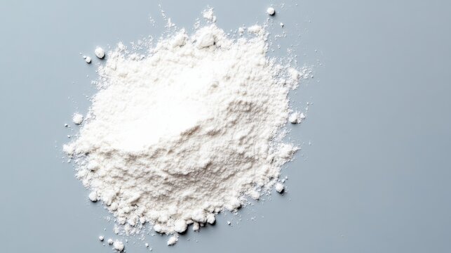 White powdery substance is spread out on a grey surface. The powder is white and he is flour