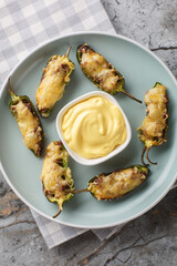 Baked stuffed jalapenos with minced meat and cheese close-up in a plate on the table. Vertical top view from above