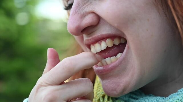 Caucasian woman picking her teeth with her finger. 