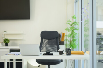 Modern office space with an organized desk, laptop, coffee cup, and stationery