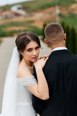 bride and groom There is green vegetation and trees around them. Hills and buildings are visible in the background