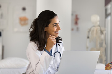 Creative thinking in medical profession. Smiling dreamy young woman doctor cardiologist sit at...