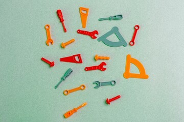 Colorful plastic toy tools on green background.