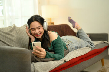 Cheerful young woman listening to music or watches a video on her smartphone