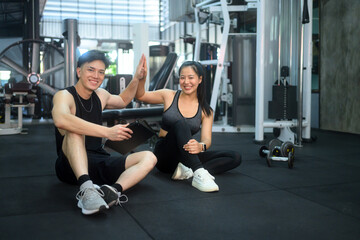 Naklejka premium Smiling trainer and client giving high five to each other after achieving fitness milestones