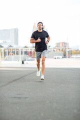 Fototapeta premium Man in athletic wear jogging on an urban street during fitness training