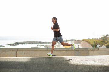 Man in sportswear running outdoors on a sunny day by the sea
