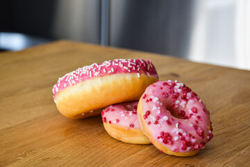 Sweet pink donut with sprinkles and strawberry topping