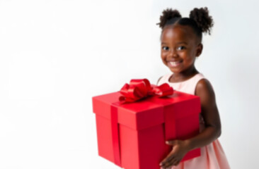 Happy girl holding a large red gift box in a bright indoor setting during a festive occasion. Blurred picture