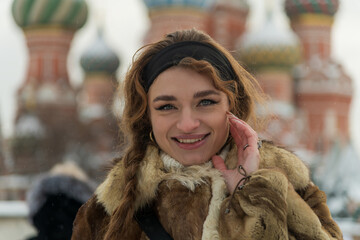 Woman smiles in warm fur coat against iconic Russian architecture in winter
