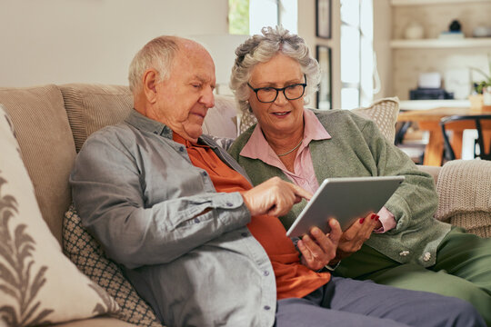 Old couple using digital tablet at home together