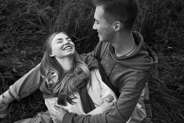 young teen couple laying on a grass on a field in september